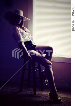 麦わら帽子をかぶった椅子に腰かける若い外国人女性の写真素材