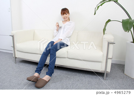 部屋でコーヒーを飲みながら普段着でくつろいでいる若い女性 4965279