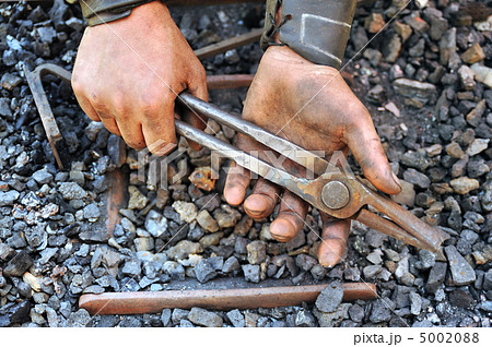 Detail of dirty hands holding pliers - blacksmith Detail of dirty hands holding pliers - blacksmith 5002088