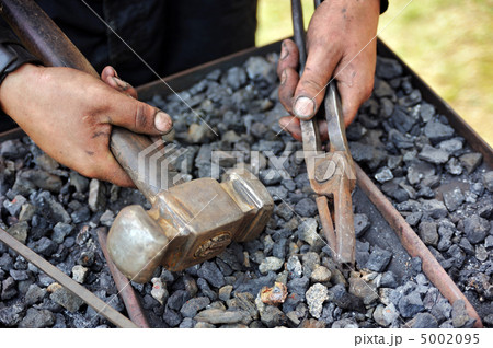 Detail of dirty hands holding hammer and pliers - blacksmith 5002095
