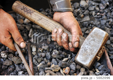 Detail of dirty hands holding hammer and rod - blacksmith 5002096