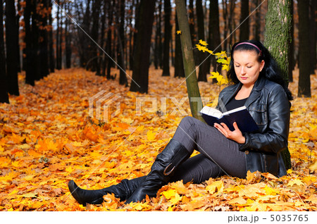 The attractive woman reads the book in autumn forest 5035765