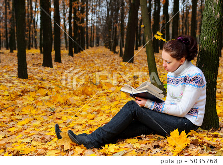 The attractive woman reads the book in autumn forest 5035768