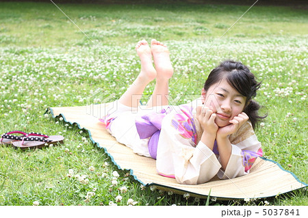 浴衣で芝生に寝そべる女の子の写真素材