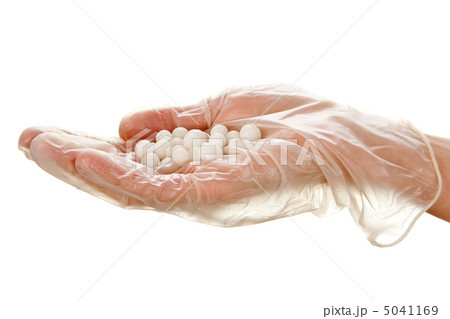 White pills on woman's palm in disposable glove 5041169