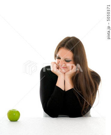 girl with grimace on her face and green apple 5050371