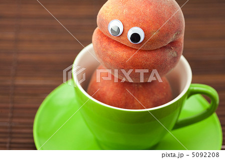 Peach with eyes in the cup and saucer on a bamboo mat Peach with eyes in the cup and saucer on a bamboo mat 5092208