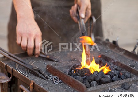 embers, fire, smoke, tools and the hands of a blacksmith 5099886