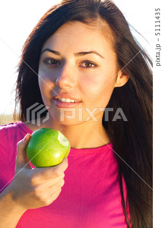 portrait of a beautiful young woman with apple  outdoor 5111435