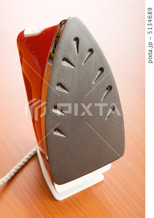 Modern electric iron on the wooden background 5134689