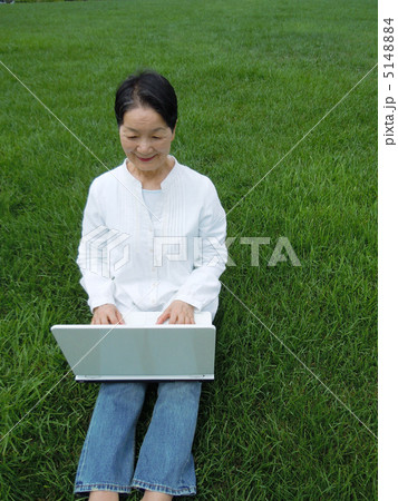 芝生の上でＰＣを楽しむシニア女性　縦 5148884