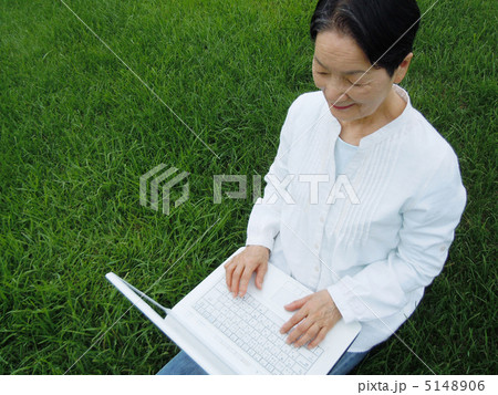 芝生の上でＰＣを楽しむシニア女性　アップ 5148906
