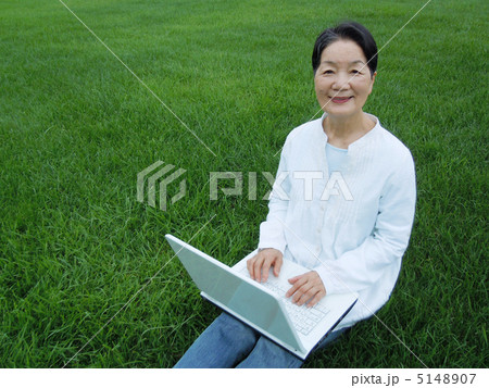 芝生の上でＰＣを楽しむシニア女性　カメラ目線 5148907