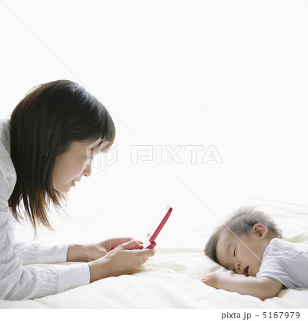 眠っている赤ちゃんと携帯電話を持つ母親 眠っている赤ちゃんと携帯電話を持つ母親 5167979