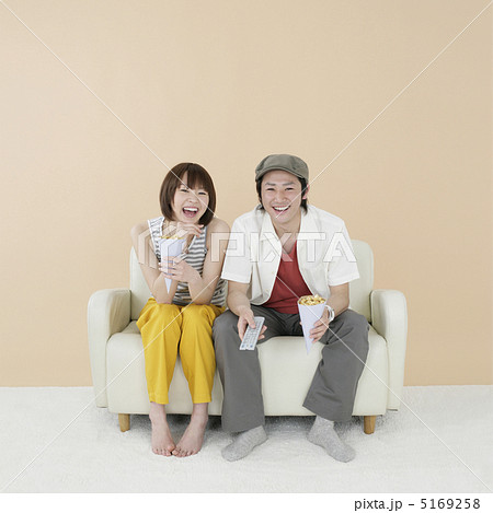 ソファに座ってテレビを見るカップルの写真素材