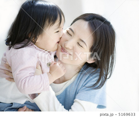 母親の頬にキスをする女の子の写真素材