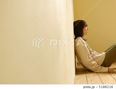 壁にもたれて座る女性の写真素材