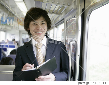 電車の中でノートを開く笑顔のビジネスマン 電車の中でノートを開く笑顔のビジネスマン 5193211
