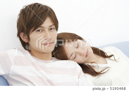 男性の肩にもたれて目を閉じる若い女性の写真素材