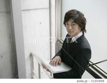 オフィスビルの階段でノートパソコンを開くビジネスマン 5193906