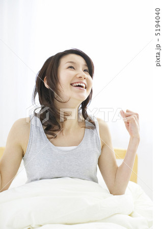 ベッドから起きる笑顔の女性 5194040