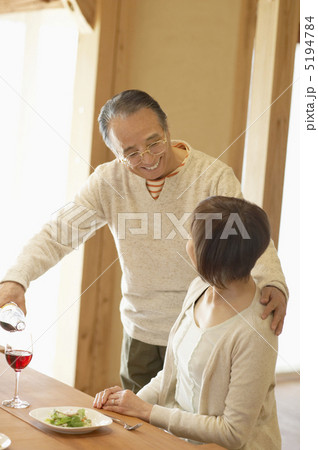 妻の肩に手を置きながらワインを注ぐ男性 5194784