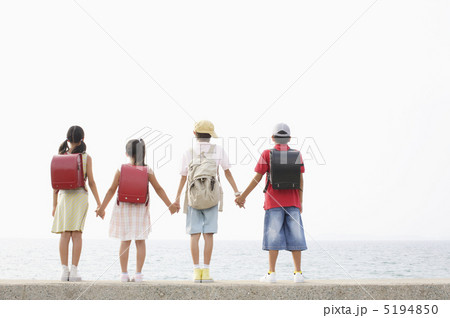 堤防で手を繋ぐ４人の小学生の後ろ姿 5194850