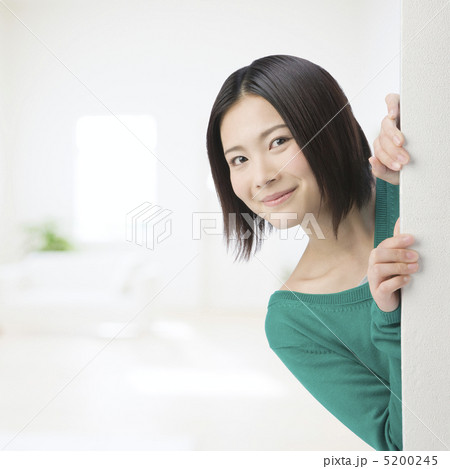壁から顔を出して微笑む女性 5200245