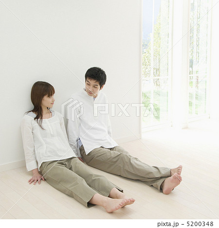 壁にもたれて座るカップルの写真素材