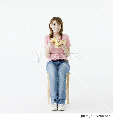 椅子に座り本を読む日本人女性の写真素材