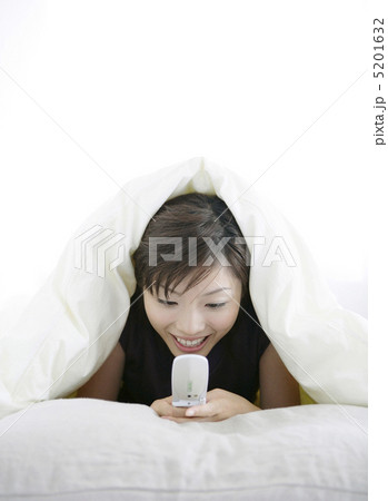 ベッドの中で携帯電話を見る女性 ベッドの中で携帯電話を見る女性 5201632