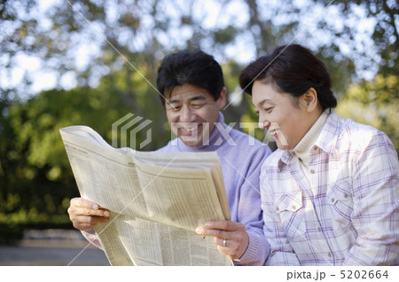 並んで新聞を覗き込む夫婦 5202664