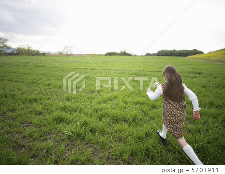 草原を走る後ろ姿の女の子の写真素材