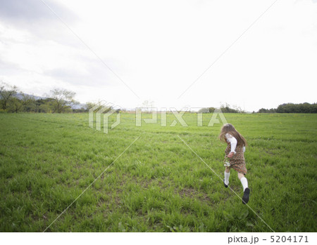 草原を走る後ろ姿の女の子の写真素材