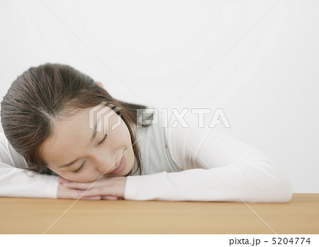机でうつ伏せで寝る女性の写真素材