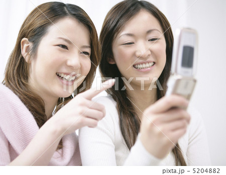 微笑みながら携帯電話を見る二人の女性 5204882