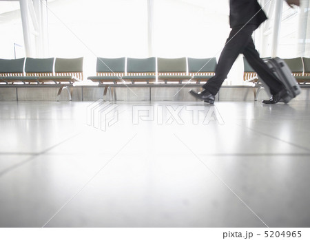 スーツケースを持って歩くビジネスマンの足元の写真素材