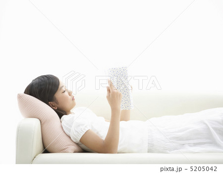 ソファに寝転んで本を読む女の子 5205042