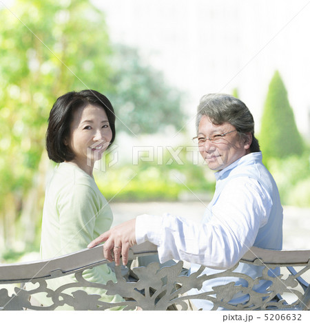 ベンチに座って振り返る笑顔の夫婦 5206632