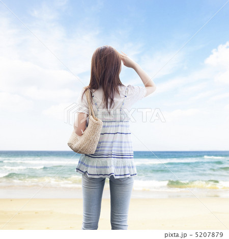 海辺で手をかざして空を見上げる女性の後ろ姿の写真素材