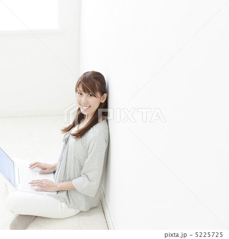 壁にもたれてパソコンを操作する女性 5225725