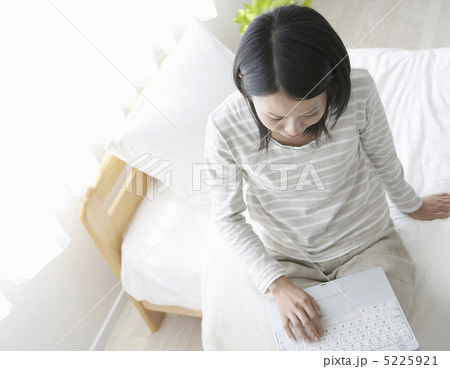 ベットに座りパソコンをする女性 5225921