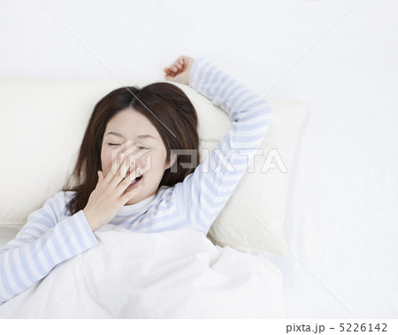 布団の中であくびをする女性 5226142