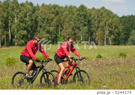 Young couple riding mountain bike in spring meadow 5244174