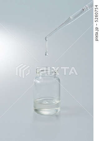 スポイトから小瓶に垂れる液体 Dropping Liquid Into A Small Bottleの写真素材