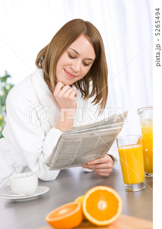 Breakfast - Smiling woman reading newspaper in kitchen 5265494