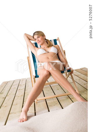 Beach - Woman in bikini sunbathing on deck chair with sand 5276007