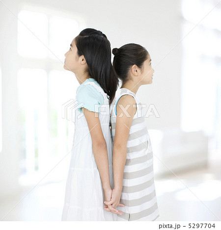 背中合わせで立つ2人の女の子の写真素材