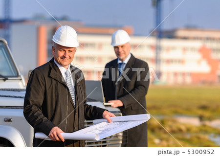 Two architects at construction site review plans 5300952