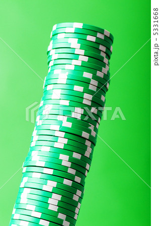 Stack of green casino chips against green background 5331668